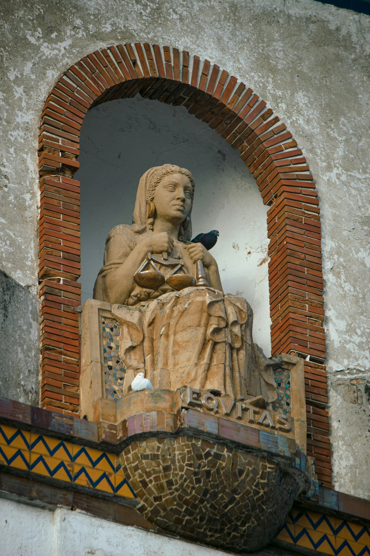 the statue in front of the window has a bird perched on it