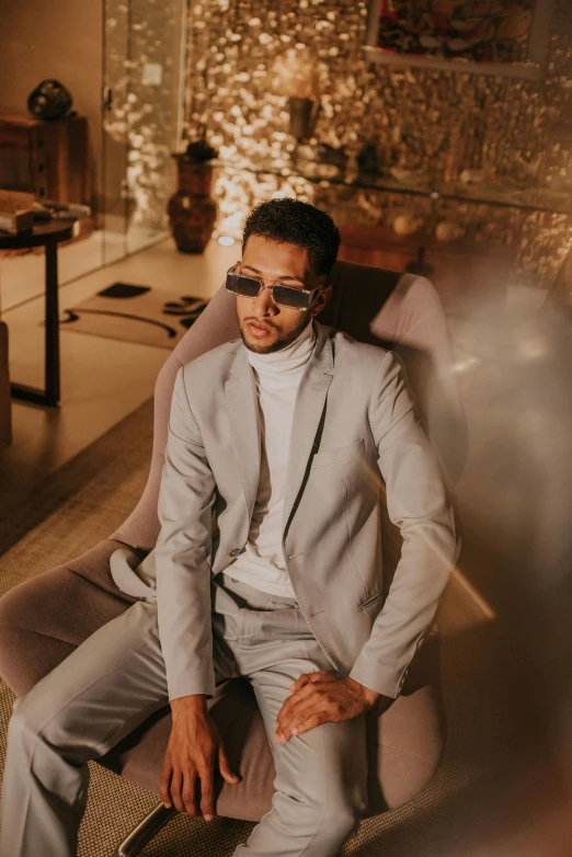 a man in a suit and sunglasses sitting on a couch