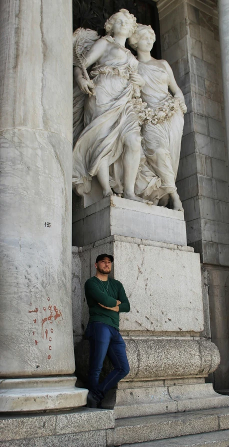 man leaning against a statue next to some pillars