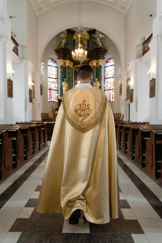 a man in a gold priests outfit standing in a church