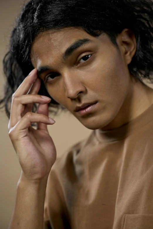 a man with curly hair holds his hand to his ear