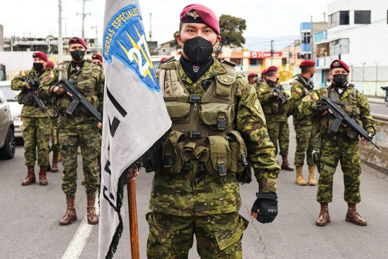 two soldiers stand with arms crossed near two flags