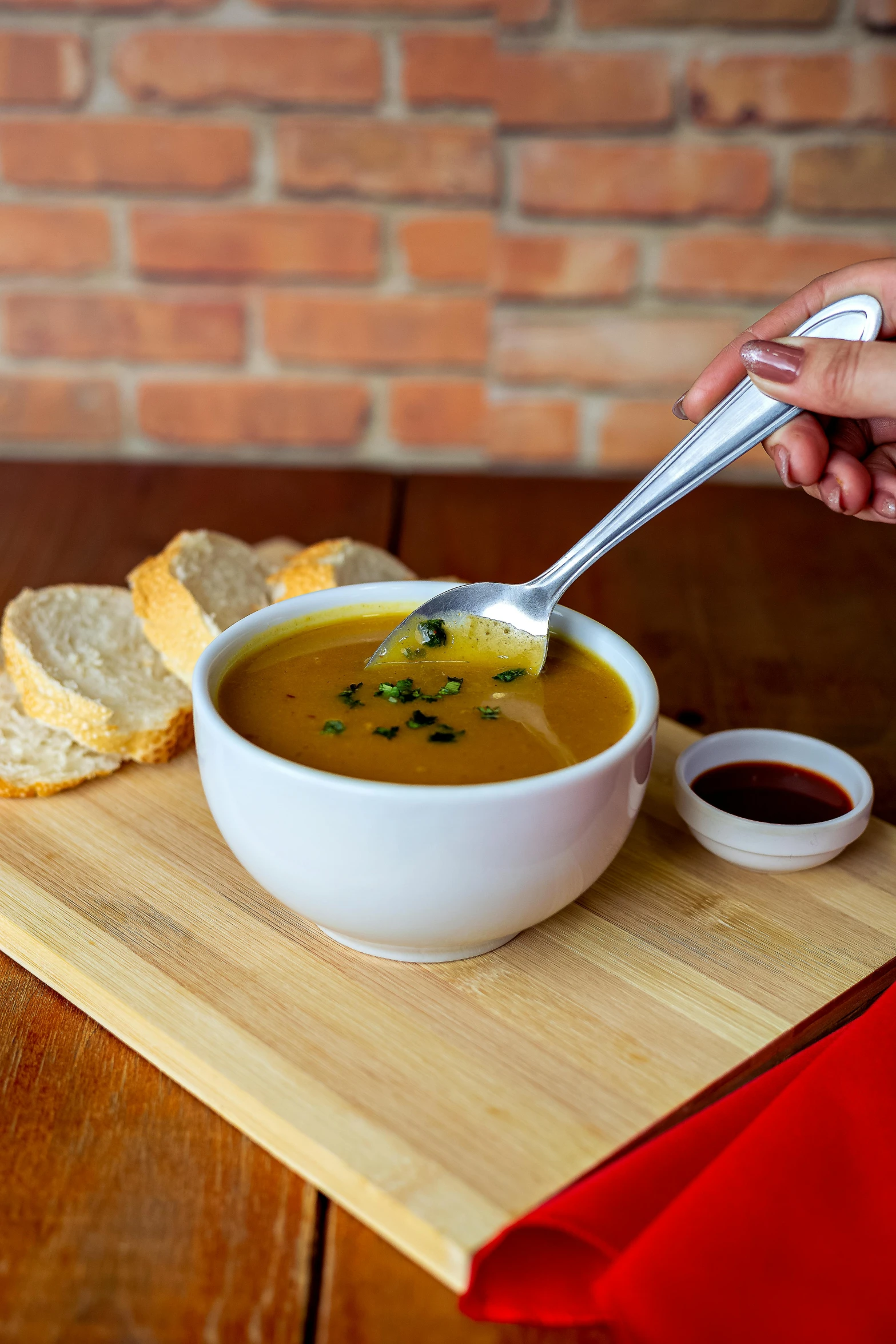 a person holding a spoon up to a bowl of soup