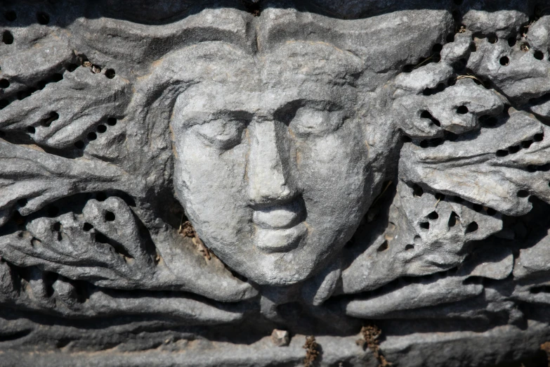 a sculpture of a head on the side of a stone wall