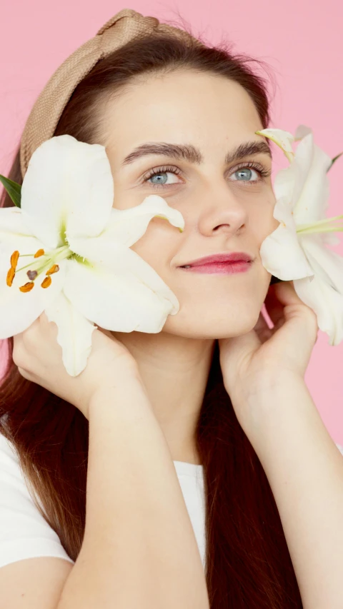 a woman holds flowers on her head to her face