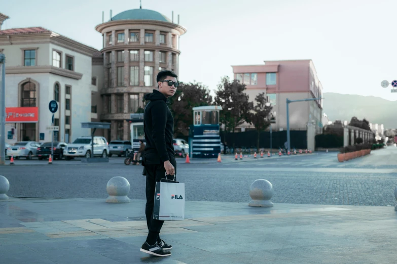 a young man standing on a sidewalk with his suitcase