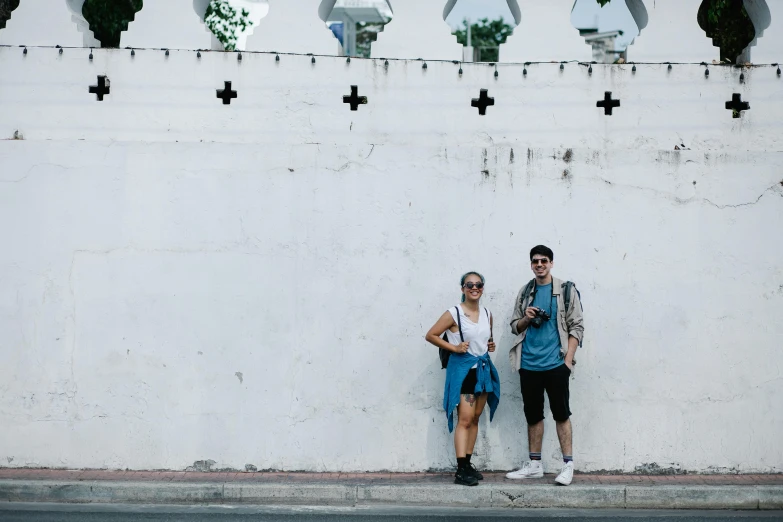 two people standing next to each other by a wall