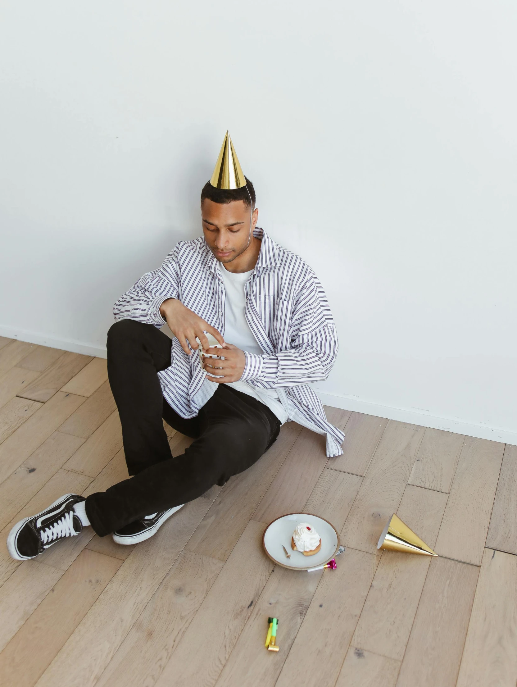 a young man in a party hat sits on the floor