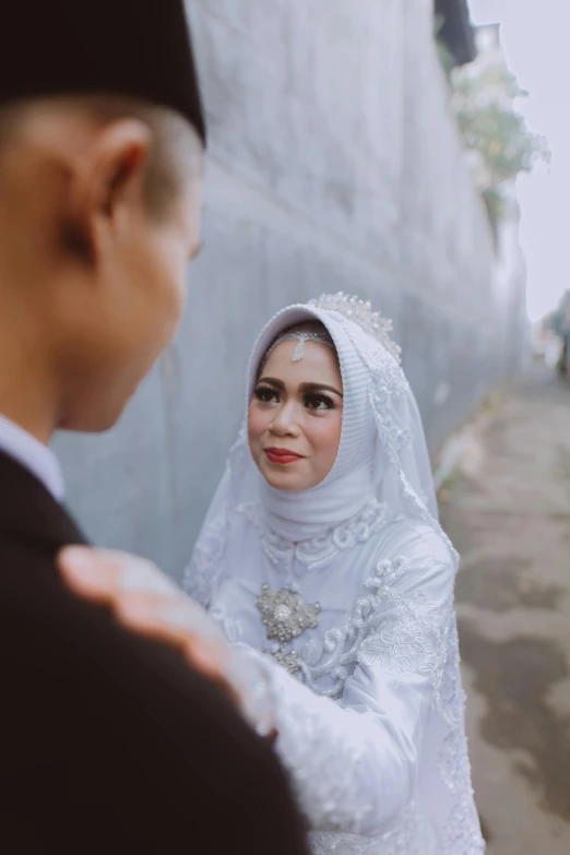 a woman in white wearing a veil next to a man