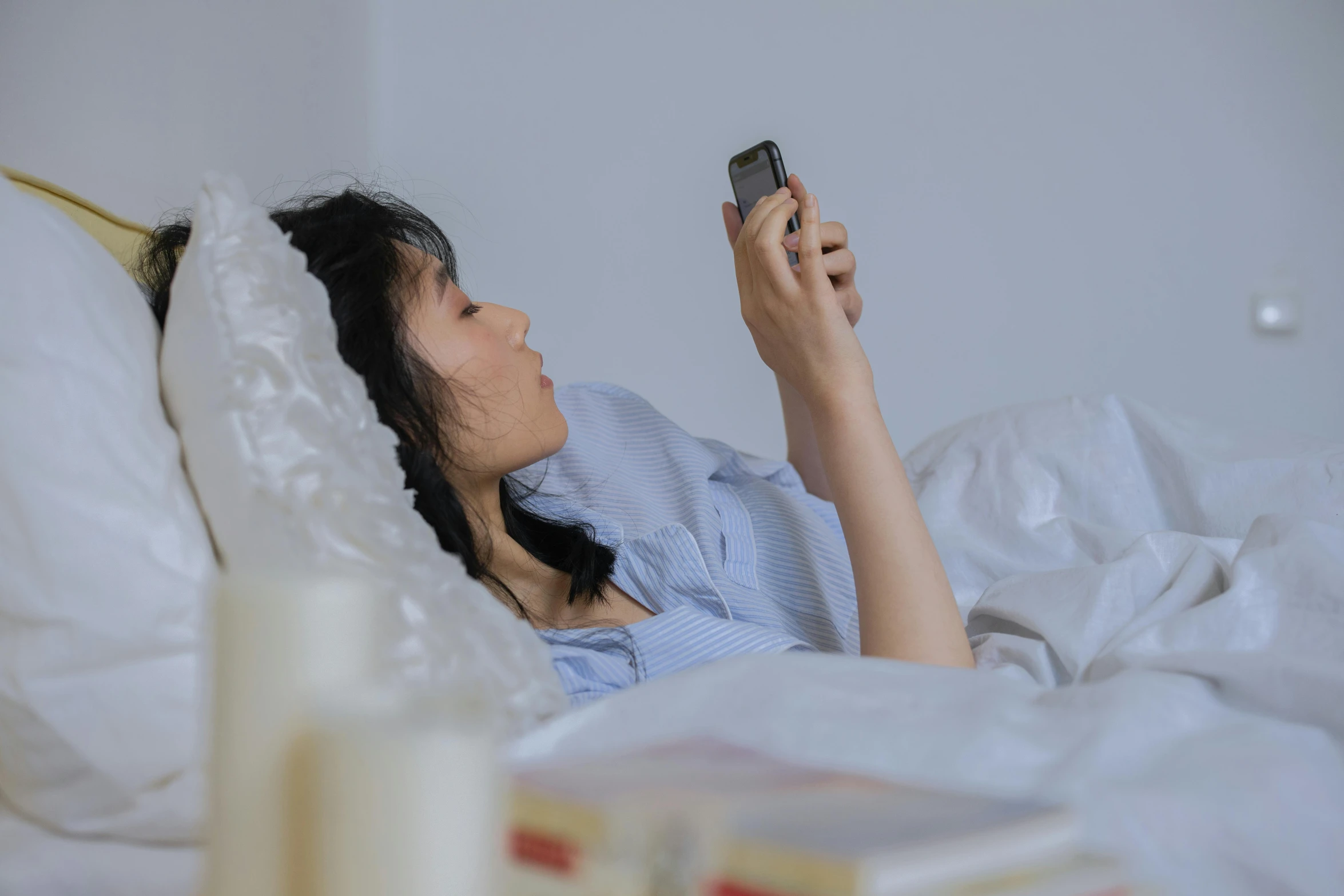 a woman laying in bed while she holds a cellphone