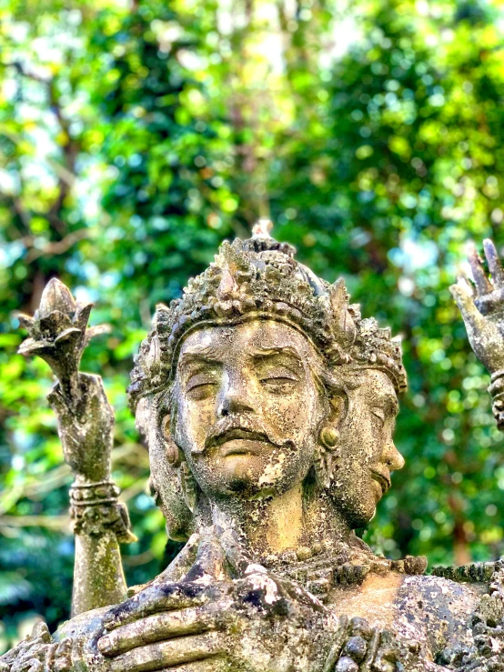 statue made from stone in front of trees and greenery