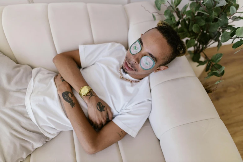 man lying on couch with green plant in background