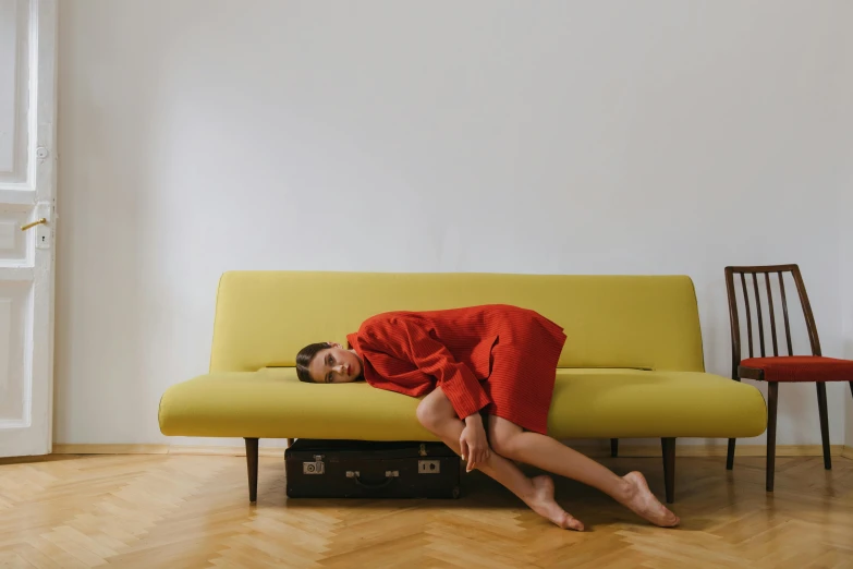 a woman is laying on top of a yellow couch