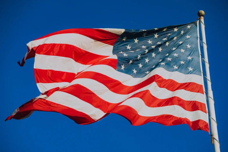 the american flag flying high in the blue sky