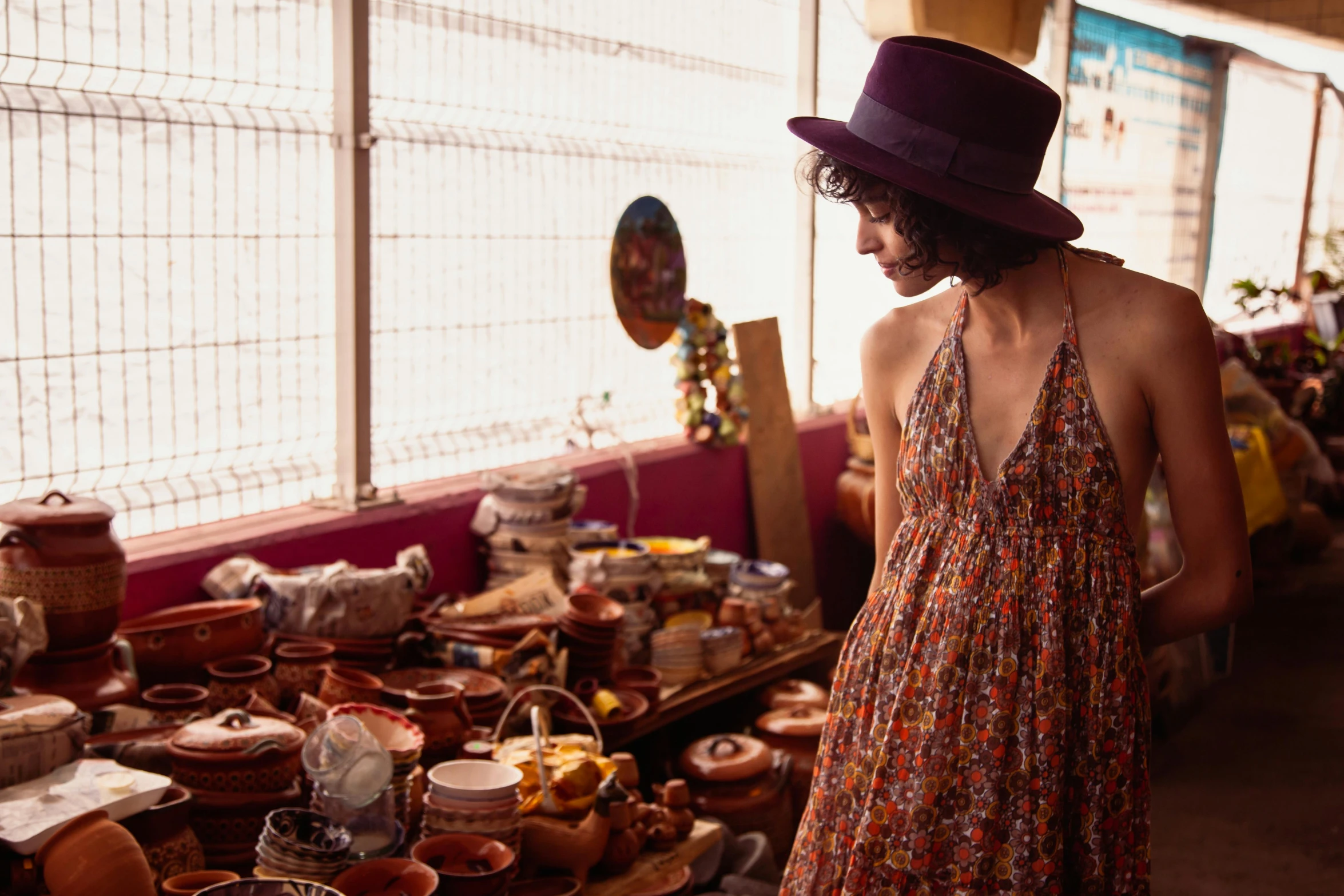 woman in floral dress standing by a stand with pots