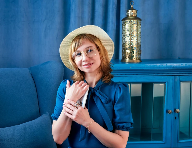 the woman is wearing a hat in front of a blue couch