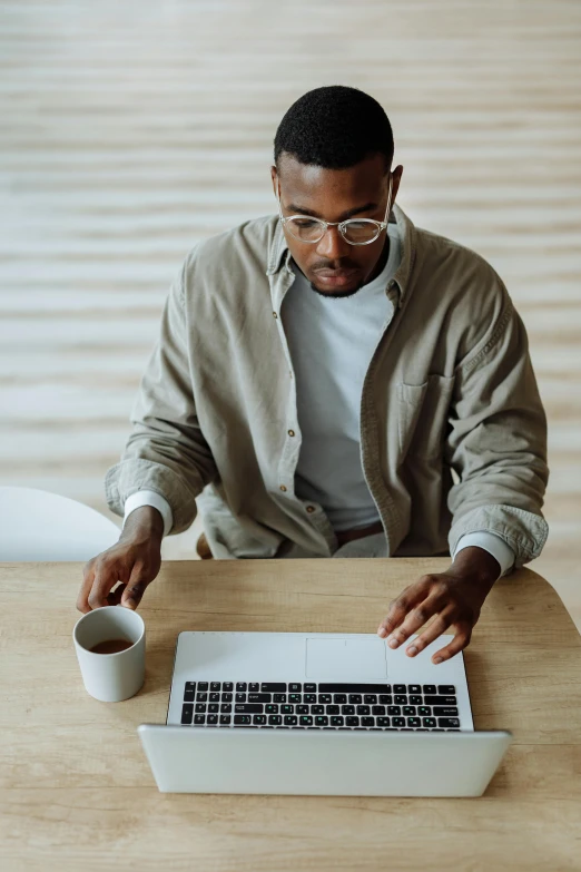 a man wearing glasses and a shirt with glasses on is looking at a laptop