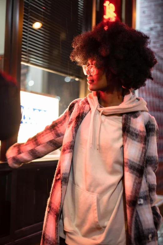 a young man in a plaid jacket and afro wig looks at his cell phone
