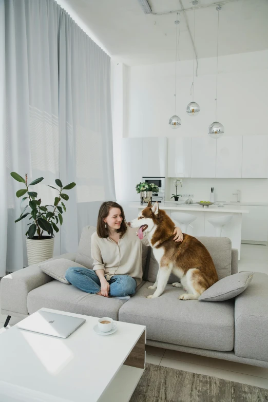 a woman sitting on a couch holding a dog in her lap