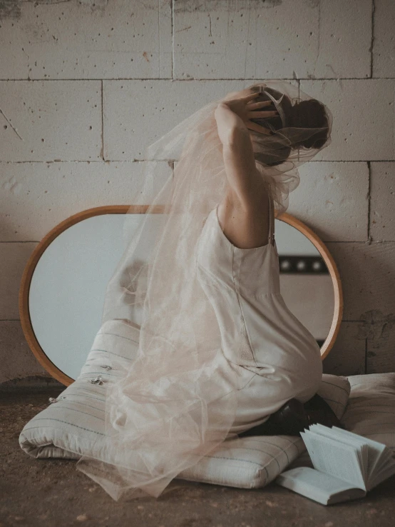 a woman sits on the floor next to a circular mirror