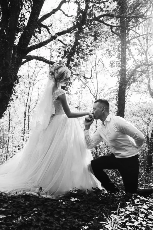 this is a man kneeling in the woods to pet his bride