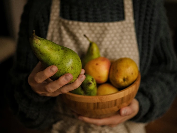 a person holds a bowl of fruit in their hands