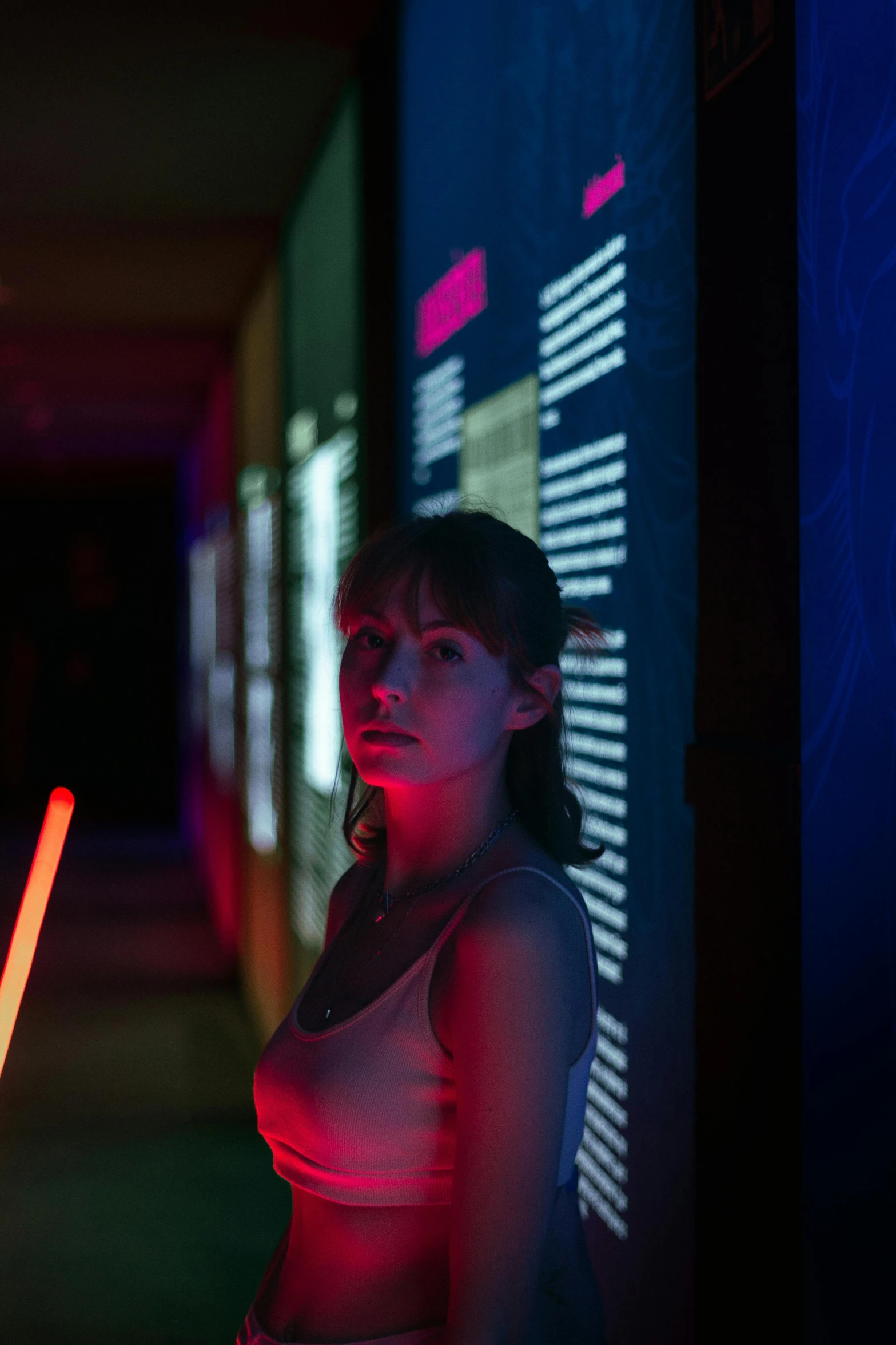 a woman standing next to a wall with an electronic light in her hand