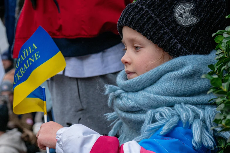 a young child with a hat and scarf holds flags