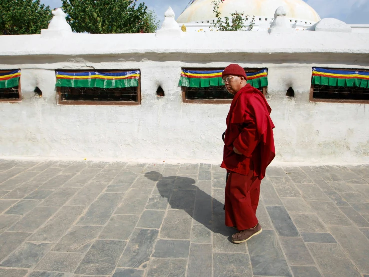 an old man is walking on a sidewalk with some colorful windows