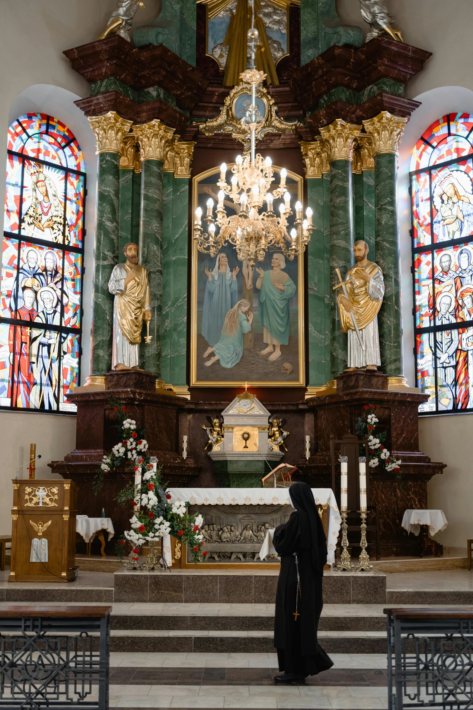 a priest stands at the alter in front of a statue