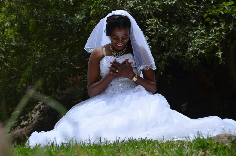 the woman is wearing a wedding dress, she is looking at her phone