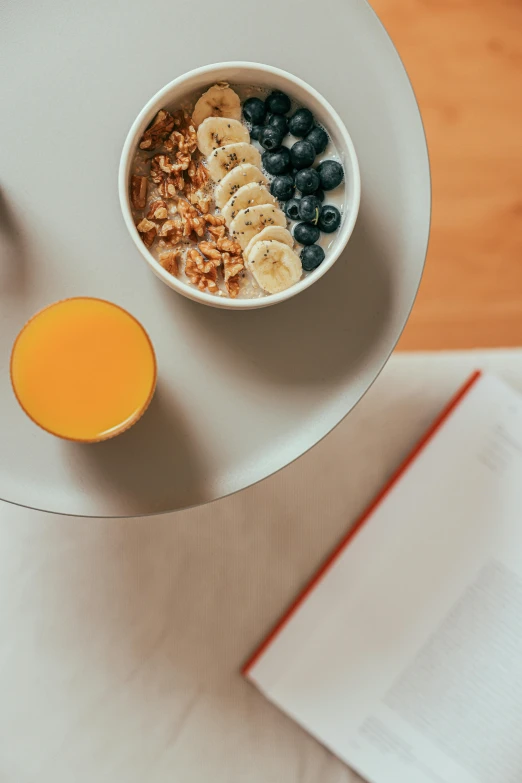 a bowl with fruits next to a glass with orange juice