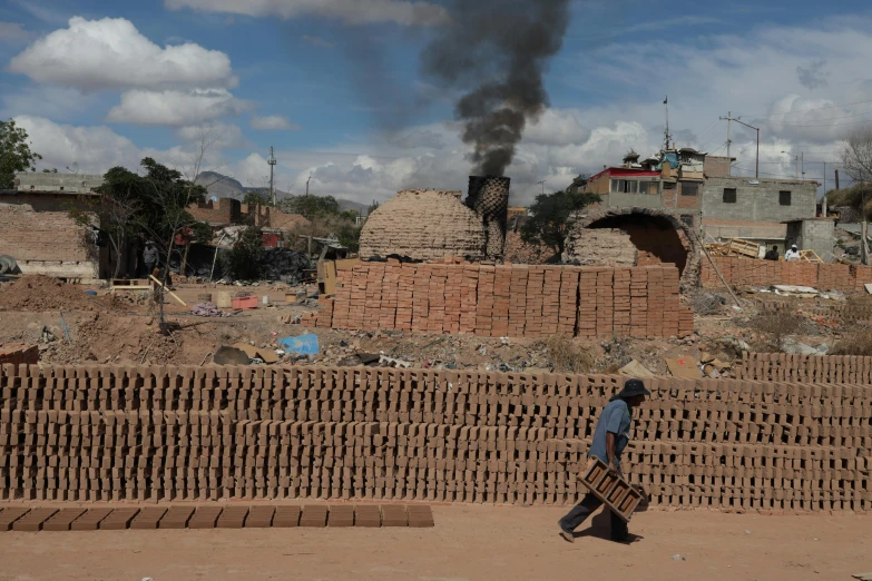 a person walks in front of a large stack of bricks