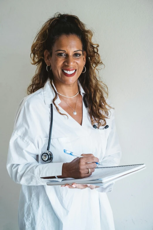 a woman wearing white smiling while holding a clip board