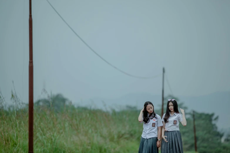 two girls walking down the road talking on a cellphone