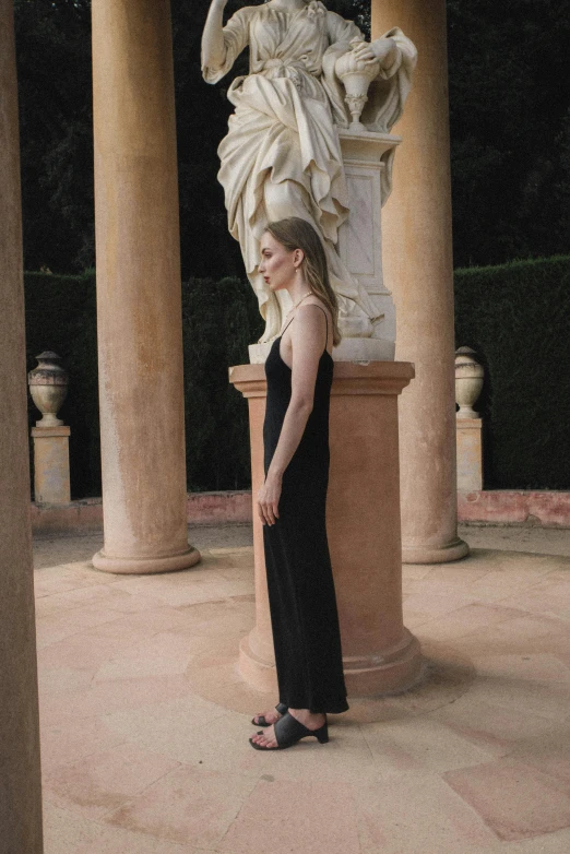 the young woman is wearing all black in front of a statue