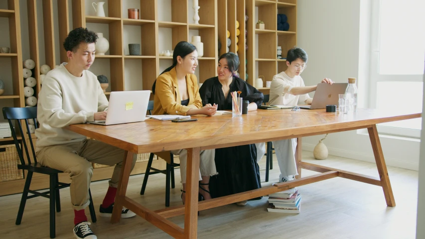 a group of people sitting at a table in front of shelves of books