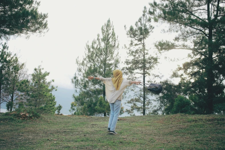 a woman throws a frisbee while on a hill