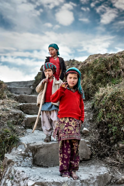 three people on a hill with one of them holding a wooden stick