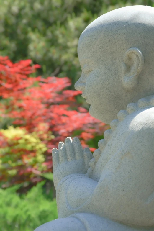 a statue of a praying person in front of some flowers