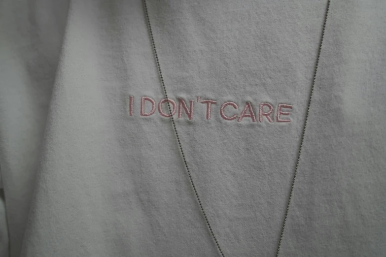 a woman wearing a white shirt and necklace that says i don't care