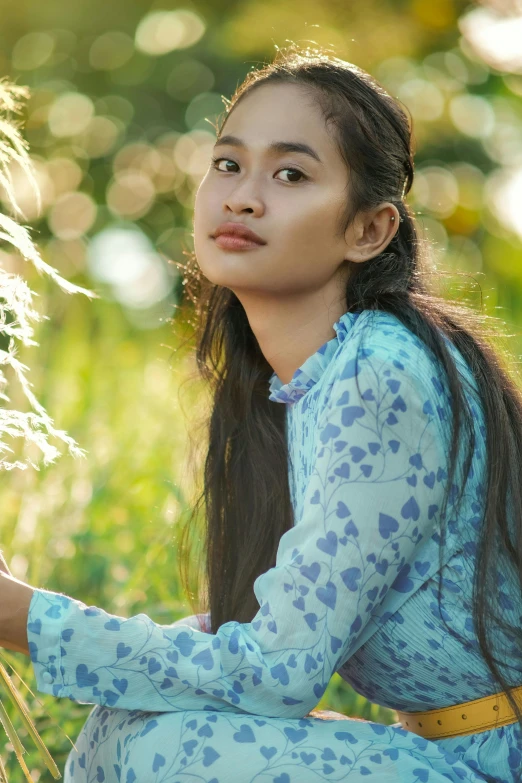 the woman is sitting in the grass with some flowers