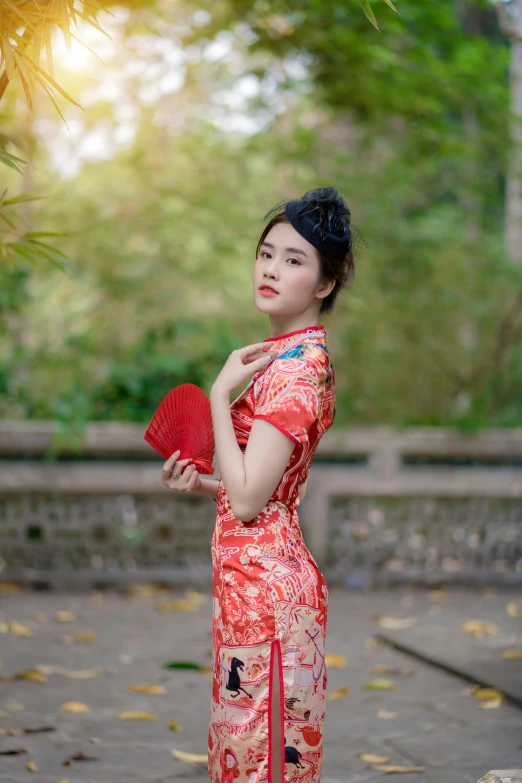 the woman is wearing an oriental dress and holding a fan