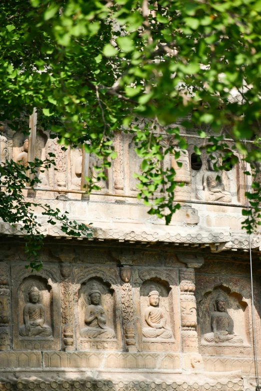 a stone building with a statue and sculptures beneath trees