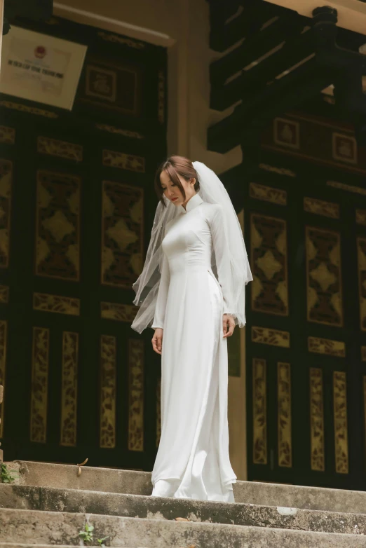 a woman in a wedding dress standing on steps wearing a veil