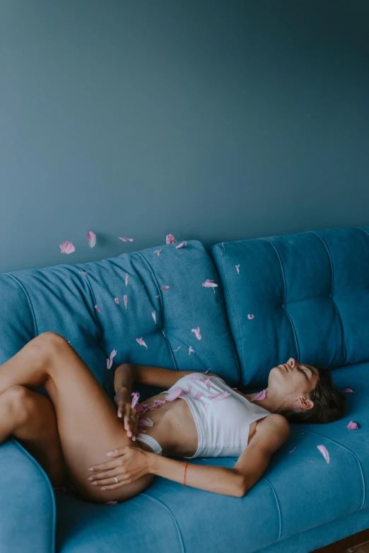 a young woman lying on a couch covered in petals