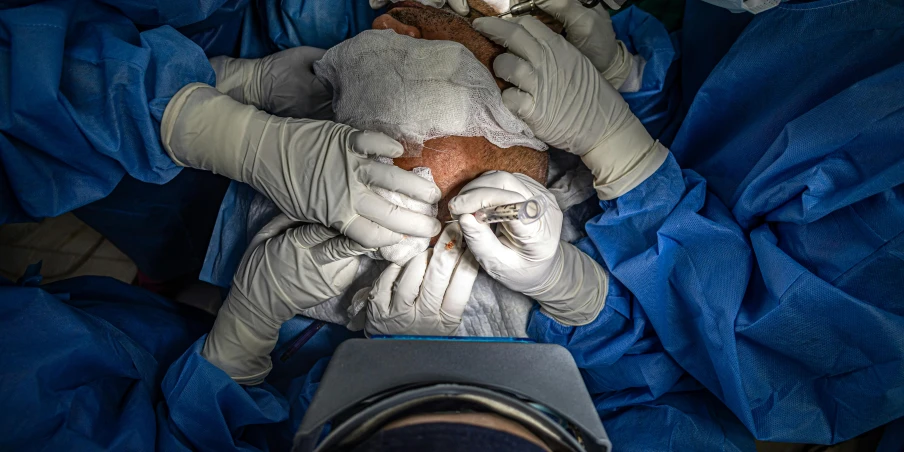 a man wearing surgical gloves covers himself in blue sheets