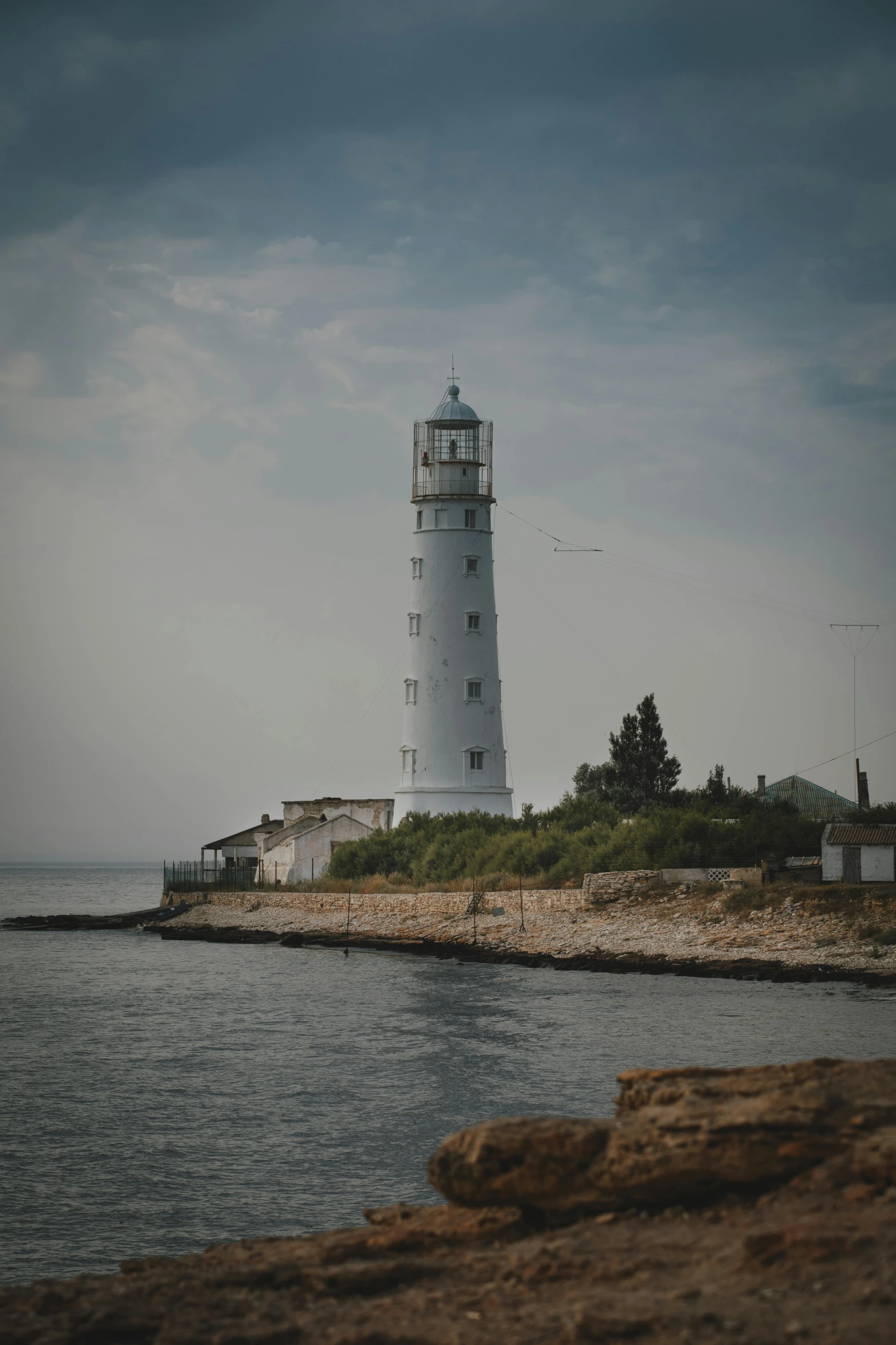 there is a white light house on the shore of the ocean