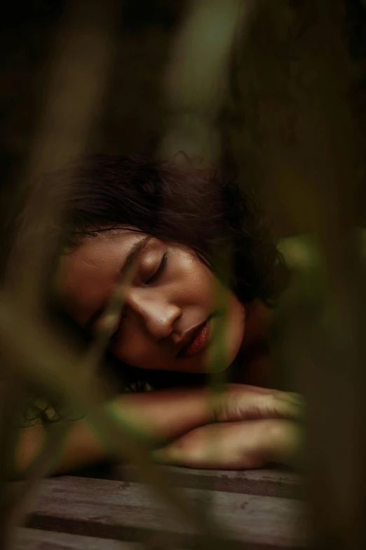 a woman laying down in a wooded area with her eyes closed