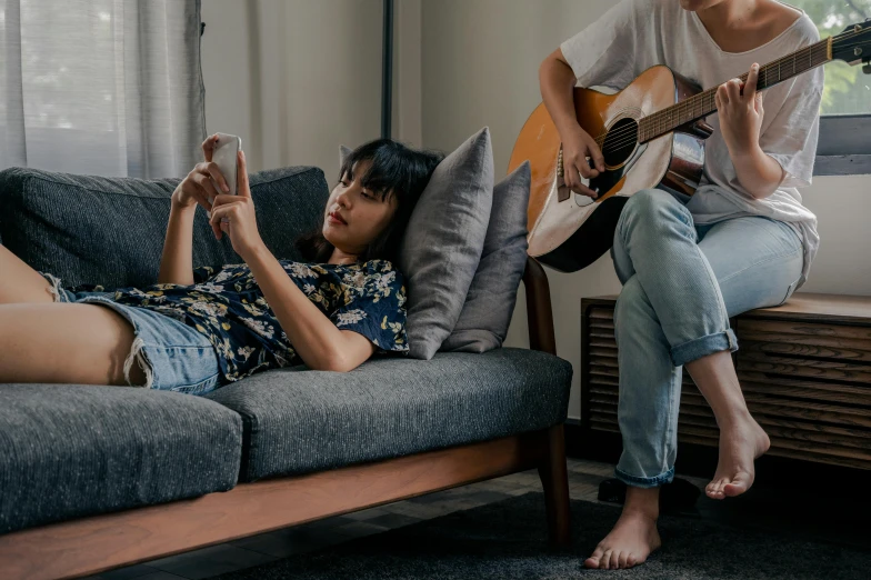 a man plays the guitar while sitting on a couch